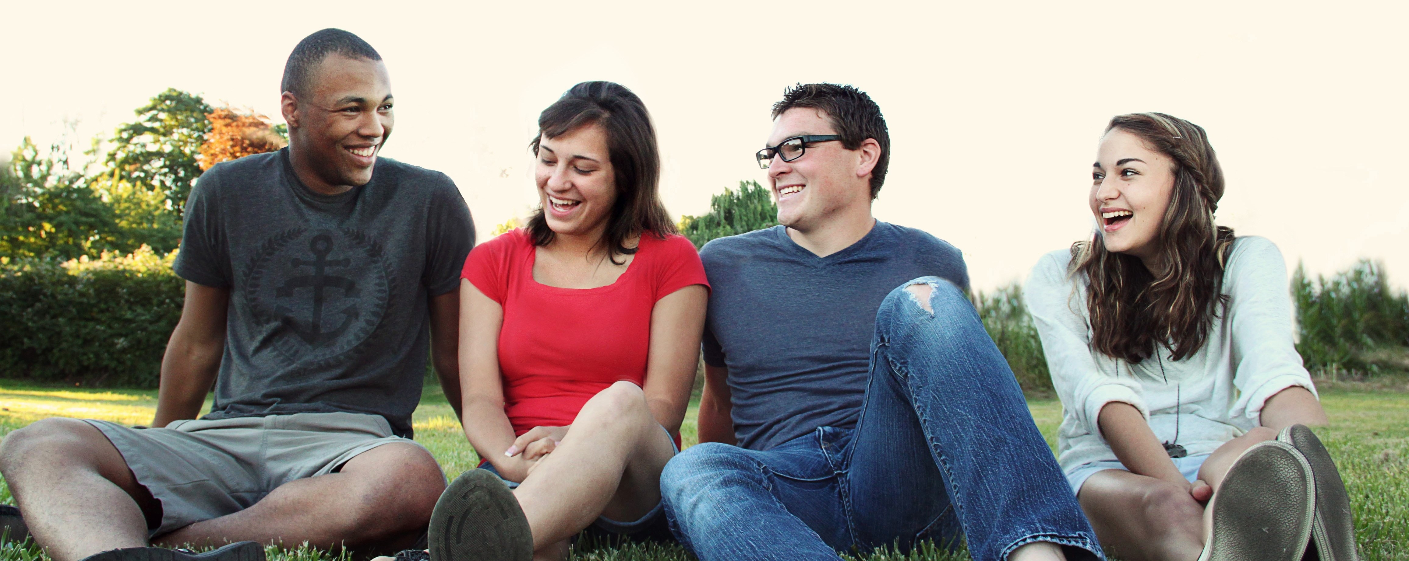 Four young people seated in a row on the grass